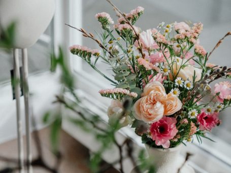 Brautstrauß Strauß aus weißen und lila Blumen, darunter Rosen und Lilien, auf einem Holzuntergrund.